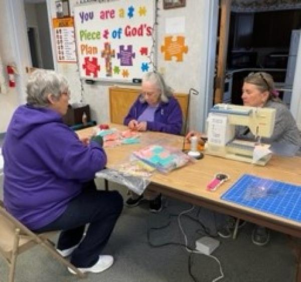 Gail LeBlanc, Doris Voyer, and Gail O'Brien work on quilt pieces during Make A Difference Day.